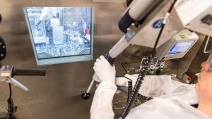 A nuclear manufacturing technician uses a manipulator arm to work samples in a hot cell.