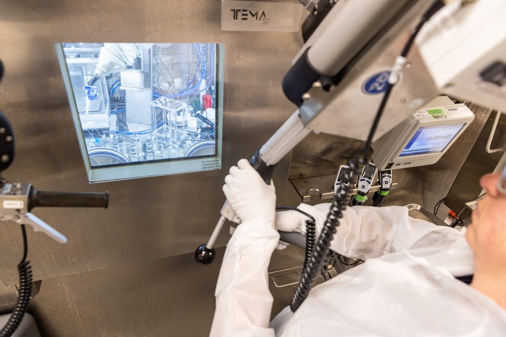 A nuclear manufacturing technician uses a manipulator arm to work samples in a hot cell.